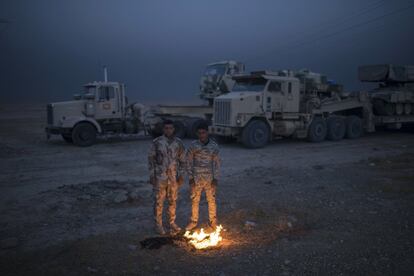 Soldados iraquíes se calientan cerca de un fuego en la base aérea de Qayara, al sur de Mosul (Irak). 