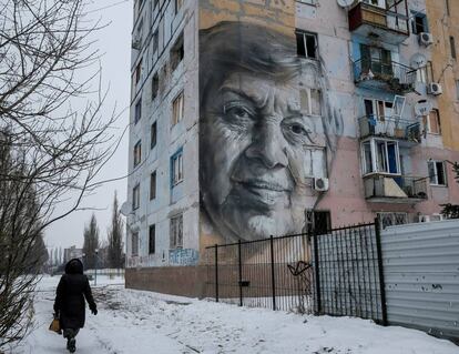 Una mujer pasa delante de un edificio dañado con un gran grafiti en Avdiyivka (Ucrania).