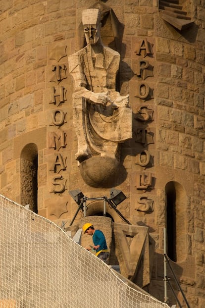 Un hombre trabaja debajo de una estatua en la fachada de la Pasión.