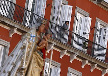 Una mujer en un balcón en la plaza Mayor de Madrid junto a la Virgen de la Almudena.