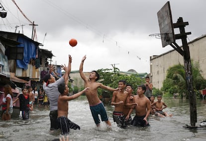 Jóvenes filipinos juegan al baloncesto en una cancha inundada en un pueblo de la región de Malabon, al norte de Manila, Filipinas.