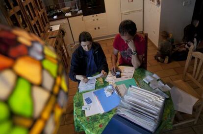 Una pareja revisa las facturas en la cocina de su casa.