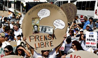 A newspaper worker holds up the cover of a newsprint reel that reads in Spanish "Without paper there's no newspaper. Free press" and images of Venezuelan and US currency in Caracas on Tuesday,