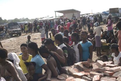 Mujeres haitianas hacen para recibir comida en un campo de refugiados de Puerto Príncipe.