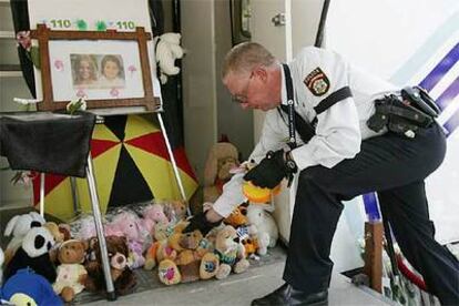 Un agente de policía deposita un peluche en el lugar donde fueron hallados los cuerpos de las niñas.