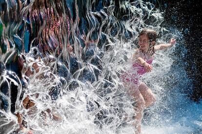 Una niña se refresca en la cascada de un parque por las altas temperaturas, en Washington, EE UU.