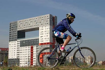 En su repertorio de sorpresas (como los molinos eólicos en la azotea del pabellón de Holanda de la Expo de Hannover), los miembros del estudio MVRDV abren en su edificio de viviendas de protección oficial un gran mirador a 36,8 metros del suelo, con una estructura de puente metálico y la intención de que la sierra de Guadarrama penetre por el hueco. El rectángulo, situado en la planta 12, tiene 14,14 metros de altura y en él se instalará una pieza de la escultora Cristina Iglesias. En colaboración con Blanca Lleó, las soluciones del equipo MVRDV, expertos en viviendas, coloristas e inventivos, elevan el nivel de una zona en construcción, la de Sanchinarro. La alegre torre de MVRDV es encargo de la Empresa Municipal de la Vivienda.