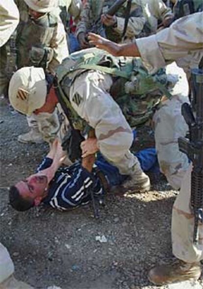 Un soldado detiene a un iraquí cerca de una planta petrolera en Rumeila.