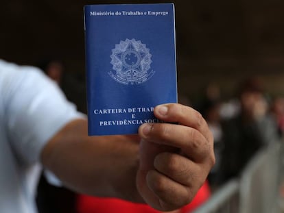 Um homem exibe sua carteira de trabalho enquanto aguarda na fila por emprego em São Paulo: idade mínima para aposentadoria deve ficar em 65 anos para homens e 62 para mulheres.