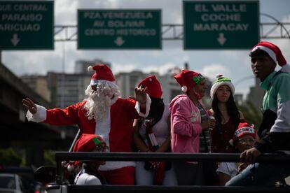 Un hombre disfrazado de Santa Claus junto a unos voluntarios vestidos de duendes.