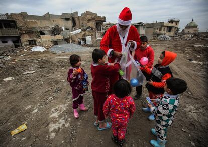 Los niños se acercan a un joven Papá Noel, que distribuye regalos para los más pequeños en la ciudad vieja de Mosul, el 26 de diciembre de 2018.