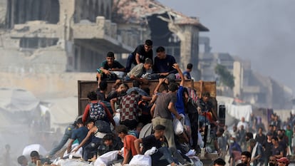 Palestinos subidos a un camión para coger sacos con ayuda, en Beit Lahia, en el norte de Gaza, el 10 de agosto.