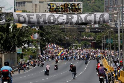 La manifestación pasa por debajo de un cartel con la leyenda "Democracia" durante la manifestación en Caracas.