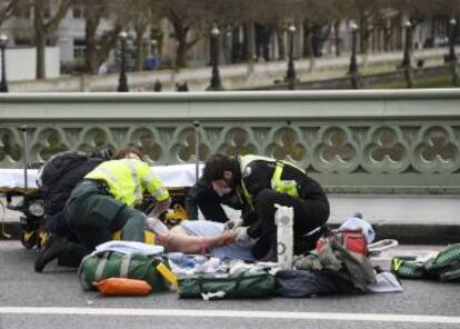 Miembros de los equipos de emergencia atienden a una de las v&iacute;ctimas del atentado en Londres.