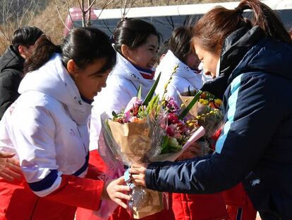 Jogadora sul-coreana entrega flores para a colega norte-coreana, nesta quinta-feira.