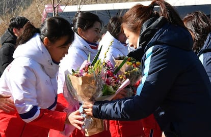 Jogadora sul-coreana entrega flores para a colega norte-coreana, nesta quinta-feira.