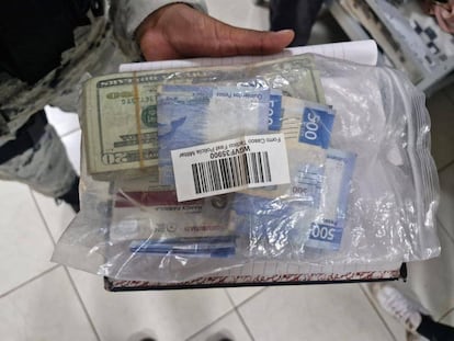 Un agente de la GN sostiene una bolsa con dinero encontrado durante el operativo. 