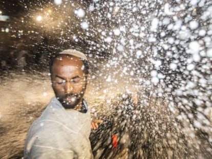 Un joven jud&iacute;o et&iacute;ope recibe el impacto de un ca&ntilde;on de agua policial en una protesta en Tel Aviv.