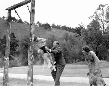 El príncipe Carlos y la princesa Ana son empujados en el columpio por su padre, el duque de Edimburgo, en el castillo de Balmoral. Junto a ellos, la Reina Isabel II y uno de sus perros. 