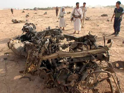 Un militar y otros hombres armados se acercan a ver los restos del coche en el que viajaban los siete turistas españoles atacados el lunes el Yemen.