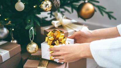 Unas manos dejando un regalo en el árbol.