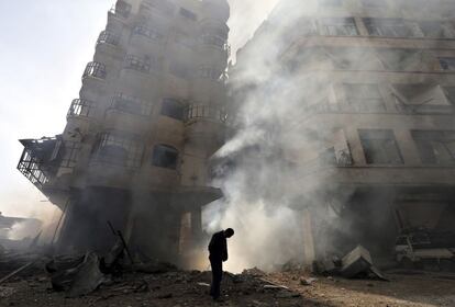 Un hombre camina frente a un edificio en llamas después de un ataque aéreo de la fuerza aérea siria en el barrio de Ain Tarma de Damasco. El 27 de enero 2013.