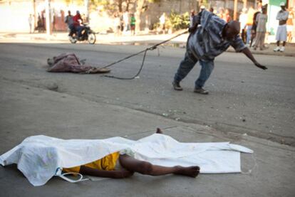 Un hombre arrastra el cadáver de una víctima del cólera en Cabo Haitiano; en primer término, el de un niño.