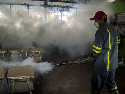 Un trabajador fumiga el salón de una escuela en El Salvador.
