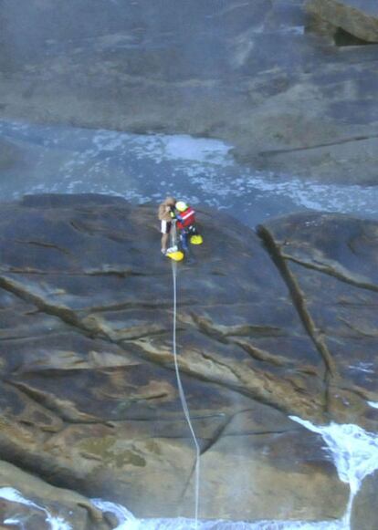 Uno de los hombres atrapados se engancha el arnés antes de ser elevado por el helicóptero del Servicio de Guardacostas de Galicia