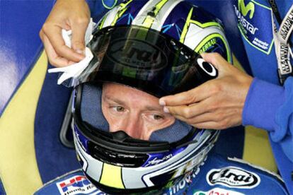 Un asistente limpia el casco de Gibernau antes de los entrenamientos libres de esta mañana.