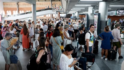 Colas de viajeros esperan la reanudación del servicio en la estación de Atocha, este martes.