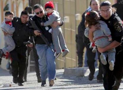 Varios policias sacan en brazos a niños de la guardería de Tijuana junto a la que se produjo el tiroteo.