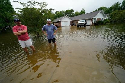 Danny González y Bob Neal atraviesan su vecindario inundado de agua después de pasar la tormenta tropical Claudette en Nueva Orleans.