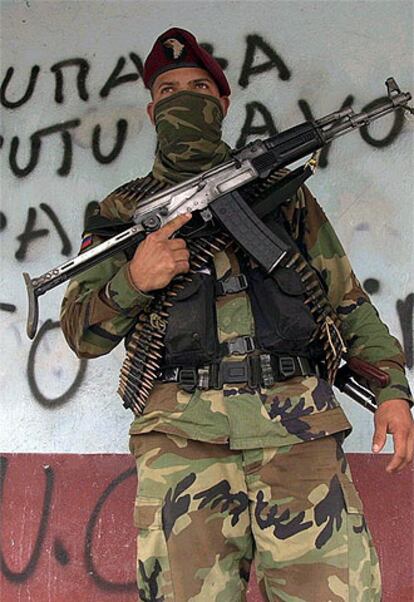 Un paramilitar colombiano posa ante un cartel contra la guerrilla.