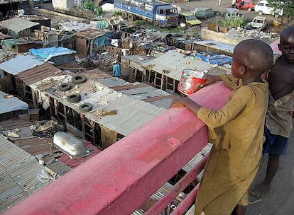 Unos niños recaudan dinero y comida con una lata entre las infraviviendas del suburbio de Colobane, en Dakar (Senegal).