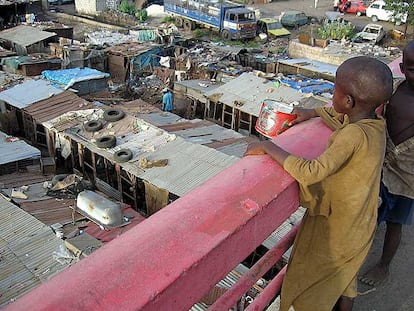 Unos niños recaudan dinero y comida con una lata entre las infraviviendas del suburbio de Colobane, en Dakar (Senegal).