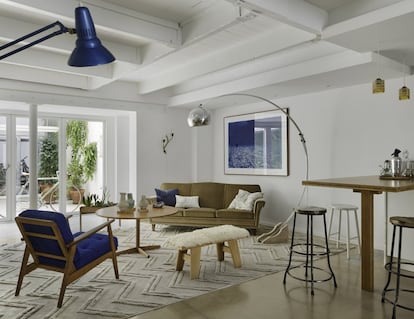 A un lado del patio queda el salón de la casa, al que se abre la cocina. Casi todo el mobiliario proviene de Noak Room, una tienda barcelonesa de diseño vintage escandinavo. Así, la butaca de teca, tapizada en azul Klein, es sueca, de los años sesenta, al igual que la mesa de centro y el sofá tapizado con terciopelo. El banco de pino, forrado con piel de oveja, es noruego; también el aplique con forma de rama y la lámpara con arco. Los jarrones son del artista australiano Cameron Fraser, la jardinera de madera de palisandro y latón es también sueca, y la lámina de la pared, una obra de los artistas Kind of Cyan. La alfombra es de la marca BSB.<br><br>El pasado de este lugar ha sido transformado, pero no borrado. Más allá de la escalera, las molduras del techo hablan de él, el mobiliario delata una nueva oportunidad para la mejor artesanía, y el patio y la actividad en torno a él remiten a la sensatez, la sostenibilidad y una plácida vida cotidiana.