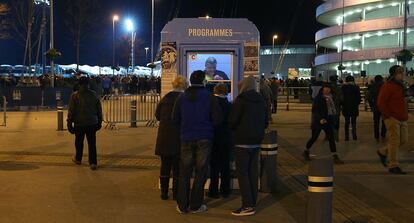 Una decena de aficionados hacen cola para recoger la revista oficial del Manchester City en los alrededores del estadio Etihad.