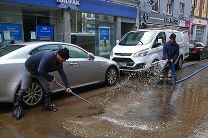 Dos hombres limpian el lodo de una calle de Pontypridd, en el sur de Gales.