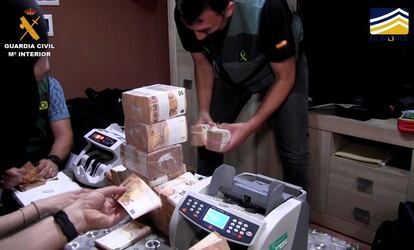 Guardias civiles cuentan dinero de los fajos de billetes requisados en la operación.