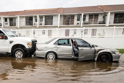 Un hombre en un automóvil es empujado por un camión a través de una calle inundada después de que los efectos del huracán Dorian llegaran a Nassau, Bahamas, el 2 de septiembre de 2019. 