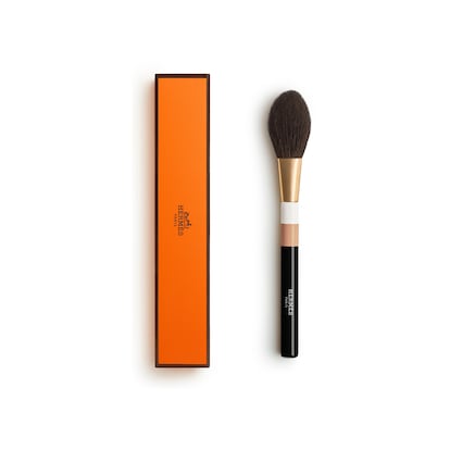 Esta brocha deposita los polvos en un delicado velo sobre el rostro. Tiene un mango largo de madera lacada y fibras naturales de pelo de cabra, de una suavidad extrema, colocadas a mano por un maestro pincelero francés. Las brochas de Hermès Beauté son objetos de coleccionista y están diseñados por Pierre Hardy, y vienen cada una en una caja naranja, característica de la 'maison'. Su precio: 157 euros.