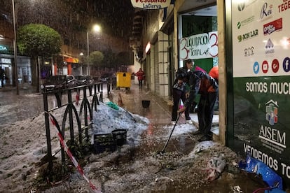 Vecinos de Arganda limpian de granizo la entrada a un local comercial.