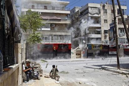 Rebeldes sirios se ponen a cubierto de los disparos de un tanque del régimen, este sábado en el barrio de Saladino de Alepo.