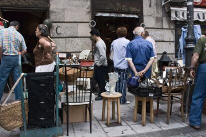 Viandantes miran objetos de segunda mano en el Rastro de Madrid.