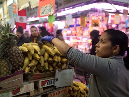 Una trabajadora manipula los productos de su frutería en el Mercado de Maravillas, en Madrid.