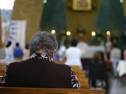 Una mujer reza sentada en un banco de una Iglesia católica.