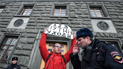 Un hombre sostiene un cartel con el lema "Putin, dimisión", frente a la sede el FSB en Moscú, este sábado, poco antes de ser detenido.