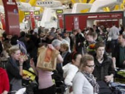 Algunas personas esperando en la T-4 del aeropuerto madrileño de Barajas tras el cierre del tráfico aéreo