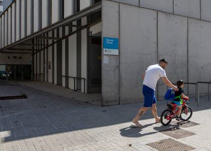 Un pare i el seu fill passegen davant d'una escola tancada al Poblenou.
